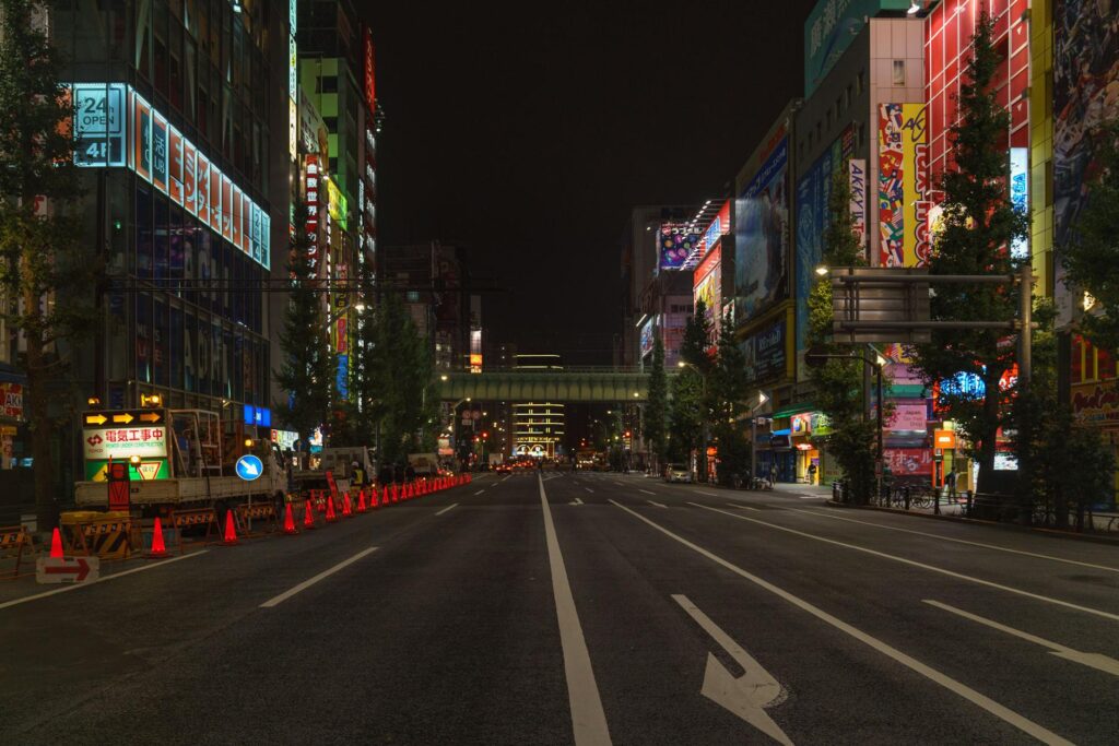 Bustling Tokyo street at night with illuminated buildings and empty road in Chiyoda City.