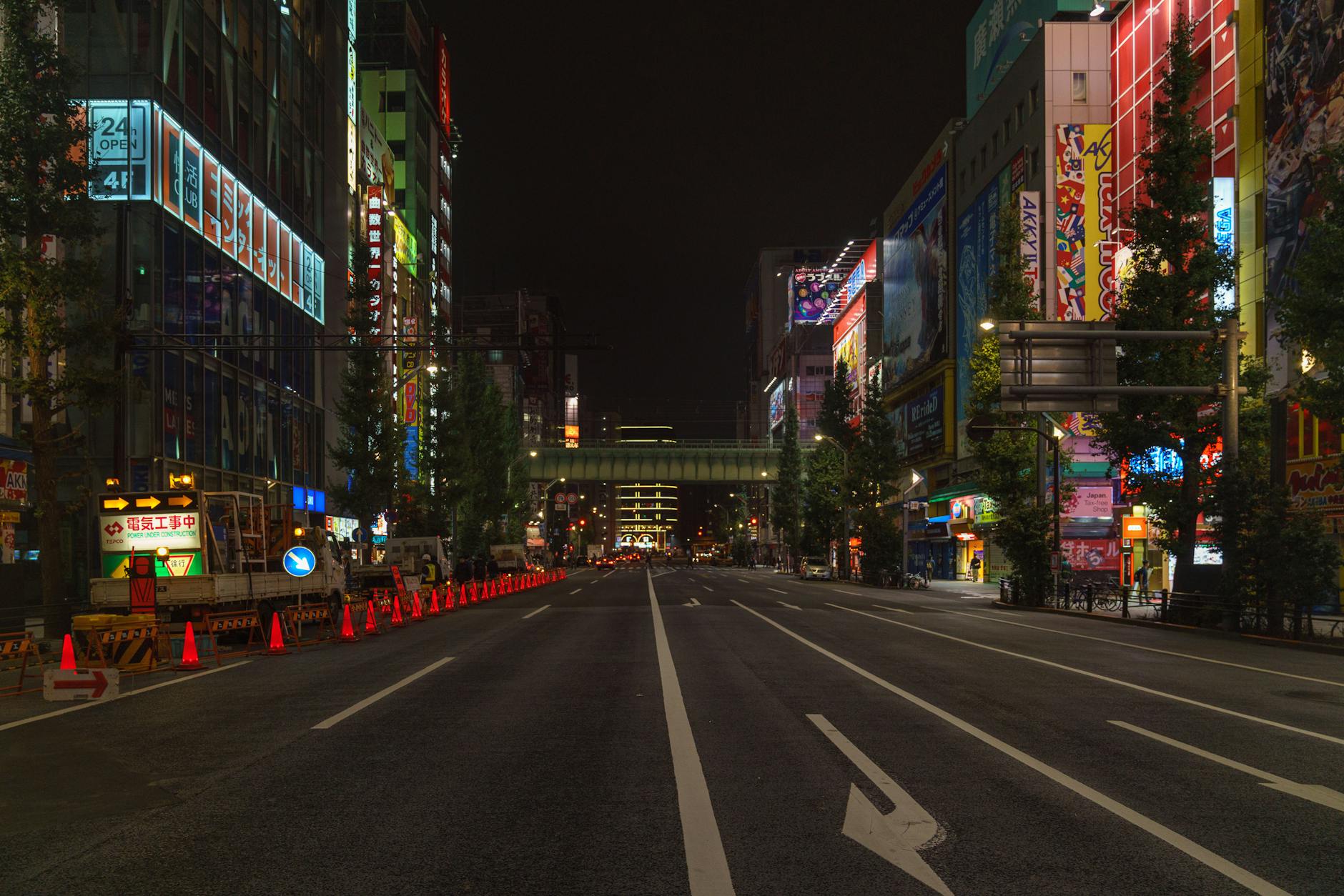 Bustling Tokyo street at night with illuminated buildings and empty road in Chiyoda City.