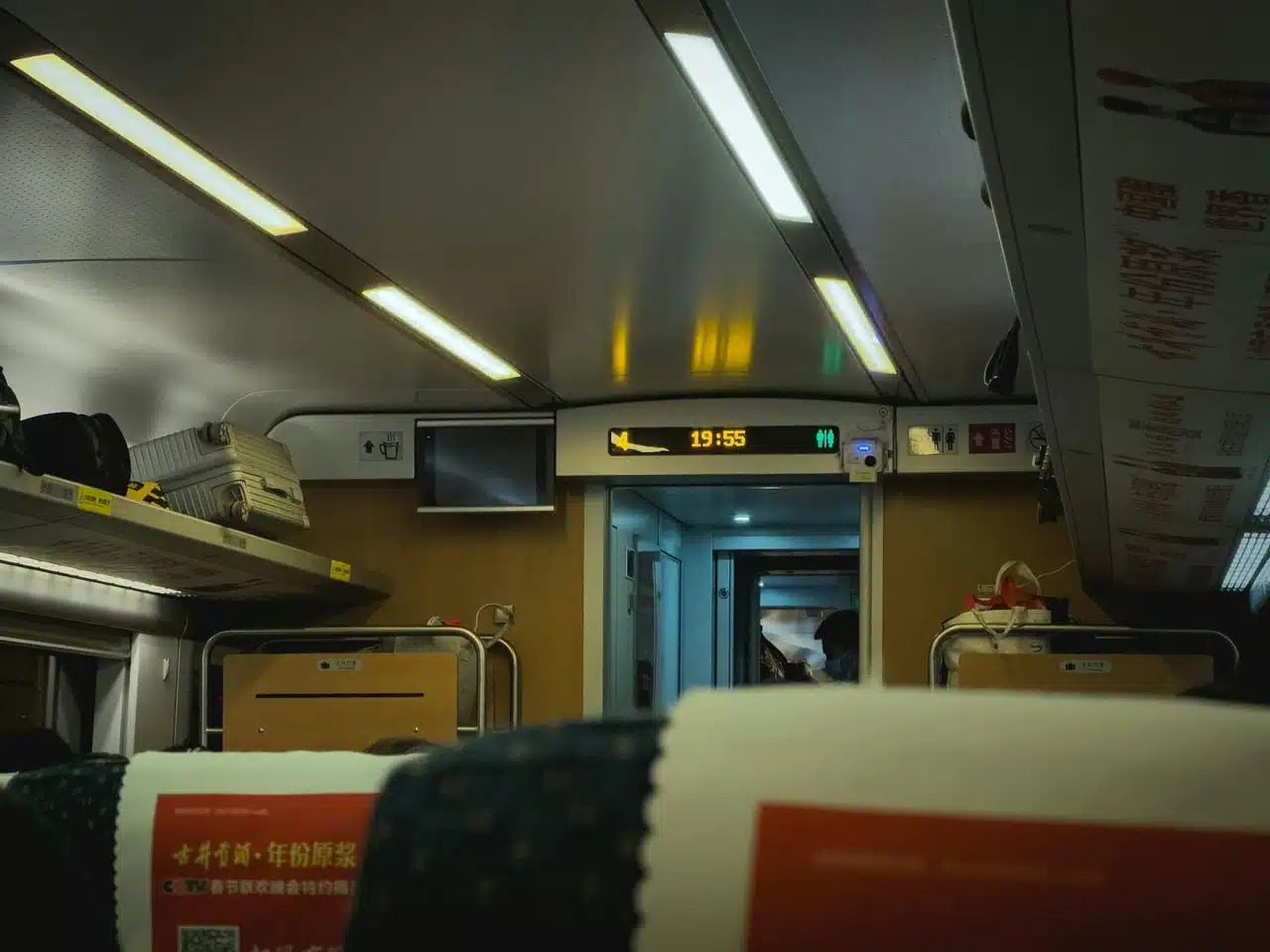 View of a modern train's interior with luggage racks and illuminated signs. Public transport ambiance.
