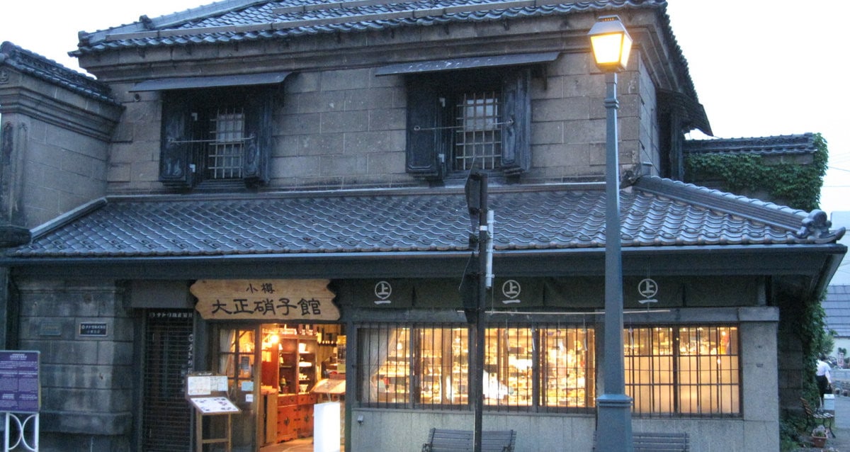 小樽大正硝子館本店的歷史石造建築外觀與夜間亮燈的玻璃商品櫥窗