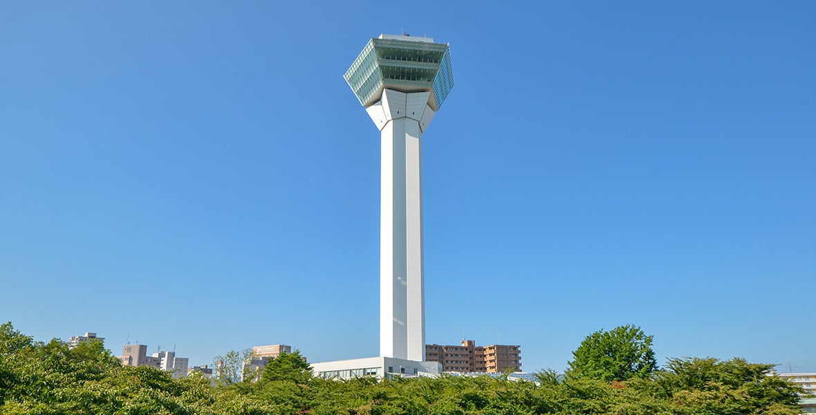 函館五稜郭塔的白色塔身與五角形展望台，襯著藍天與周邊綠樹