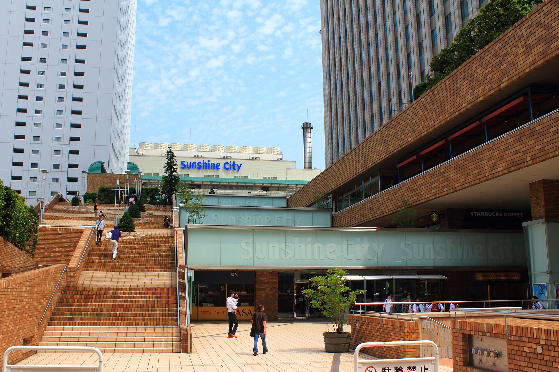 Sunshine City building entrance with brick staircase and pedestrians on a sunny day