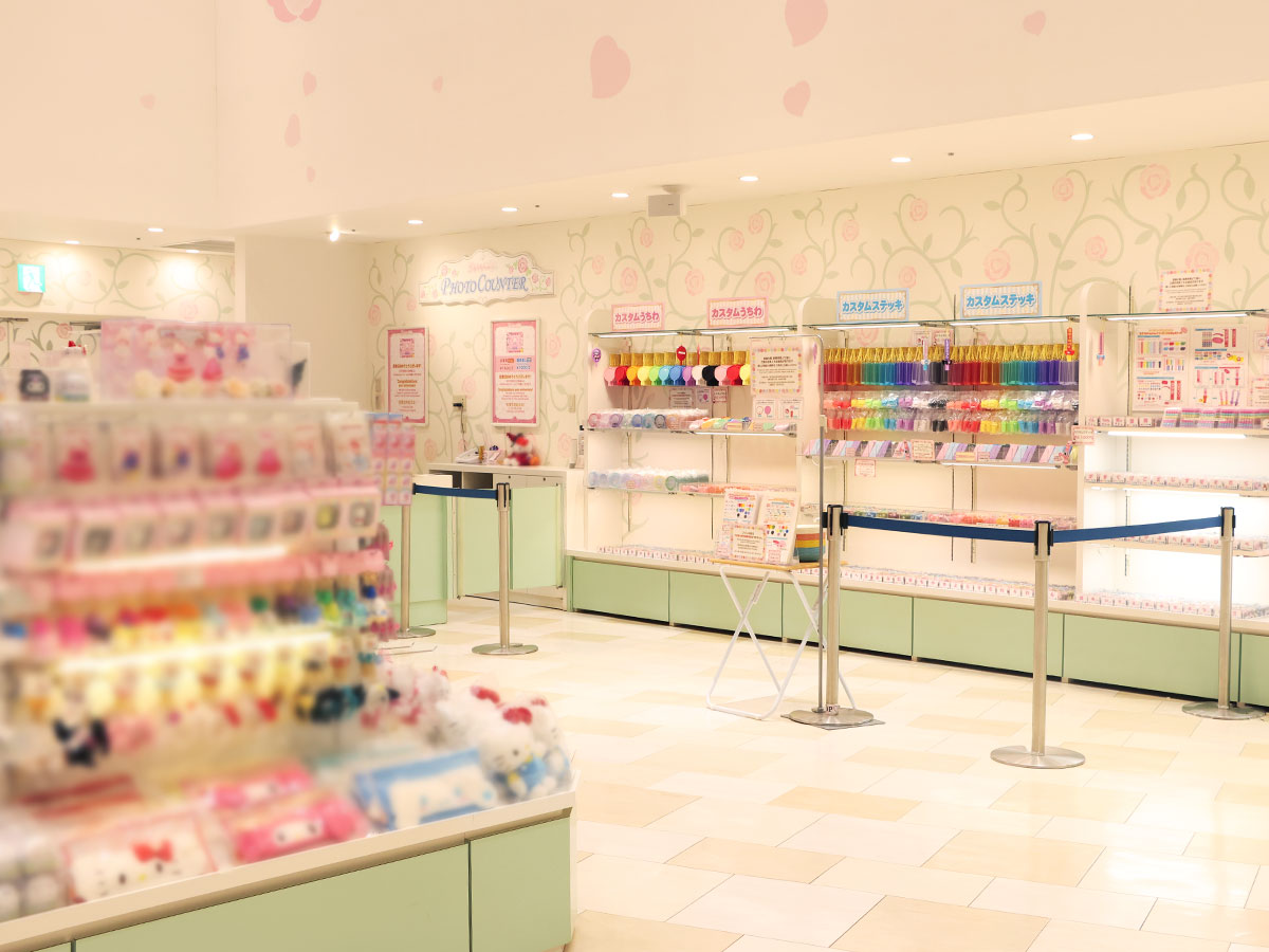 Pastel white and mint shop interior with colorful ribbons, stickers, and Hello Kitty merchandise in the foreground