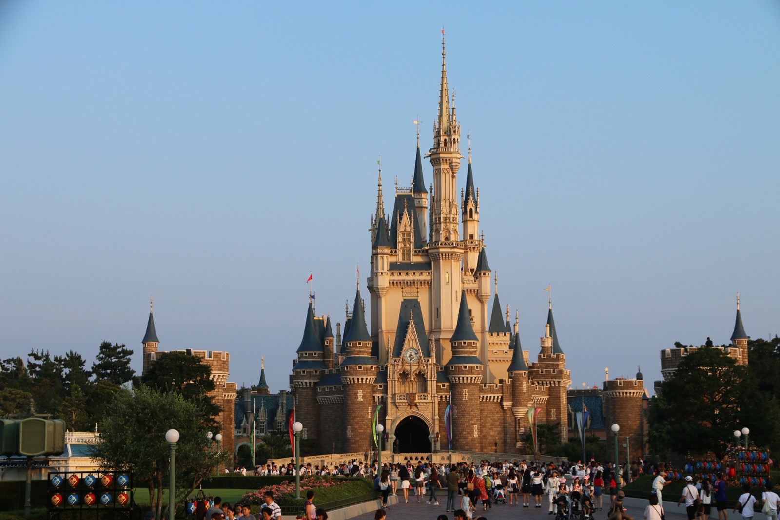 Tokyo Disney Castle at dusk with crowds of visitors in front