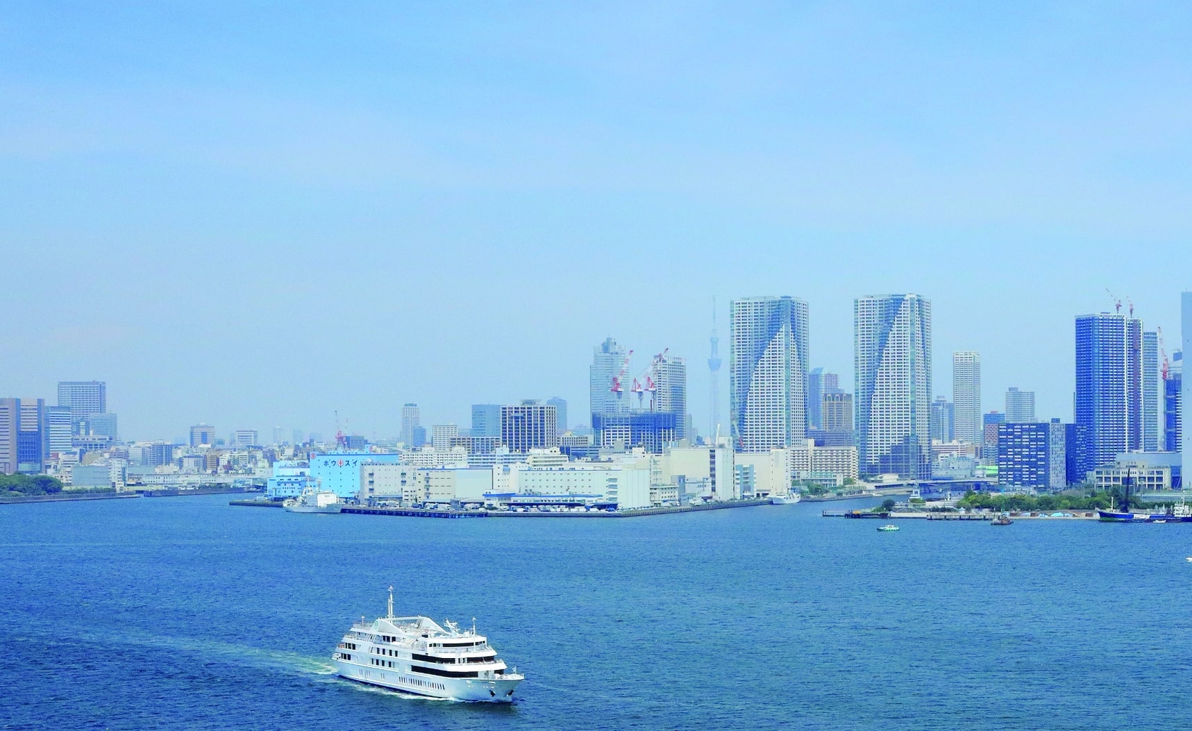 White cruise boat on blue bay with Tokyo city skyline and towers behind