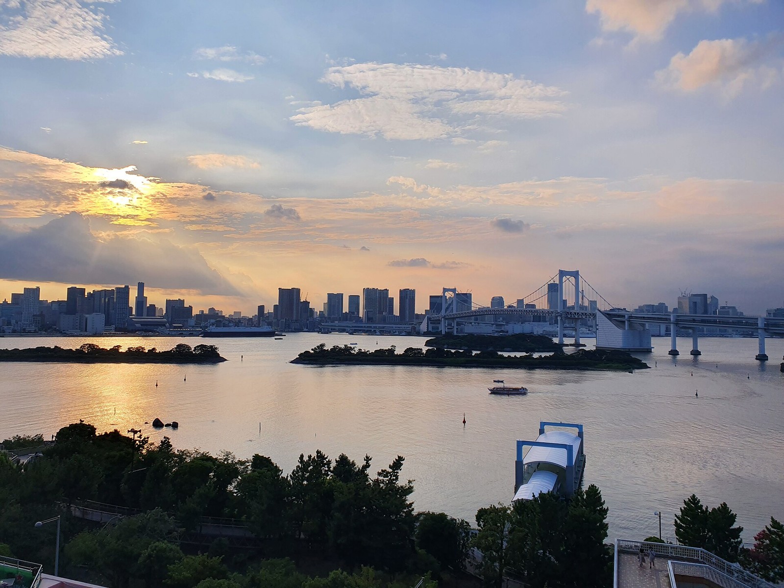 Sunset over Tokyo Bay with Rainbow Bridge spanning the water and city skyline beyond