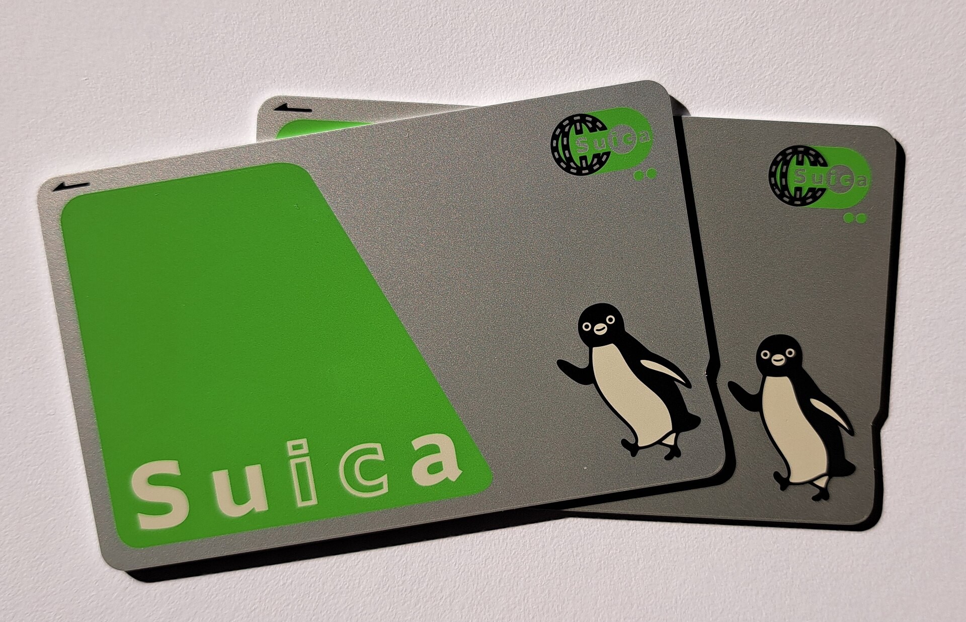 Three gray Suica cards stacked on a white surface, each with a penguin mascot