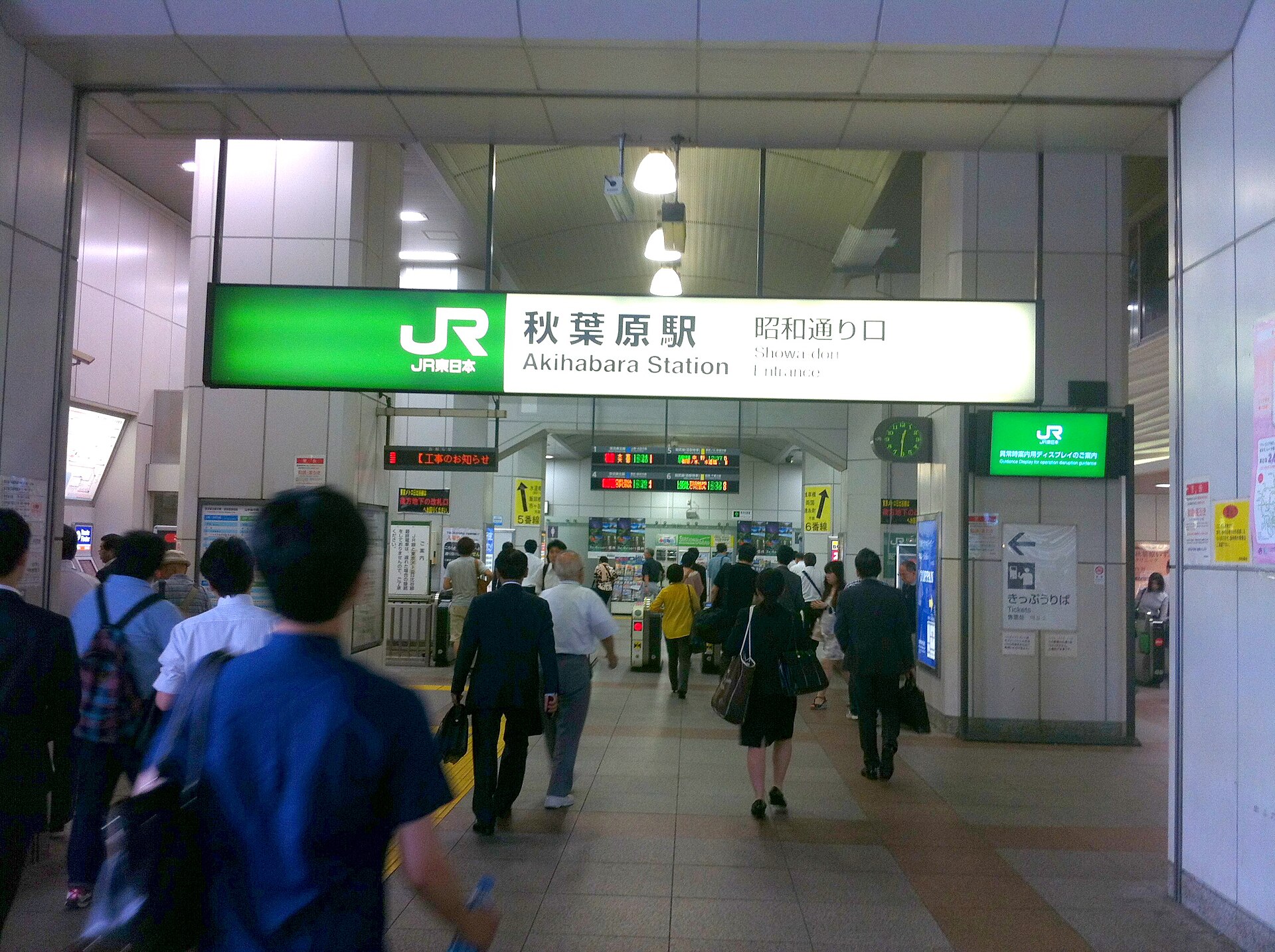 Interior of Akihabara Station with a green JR sign and commuters walking through the concourse