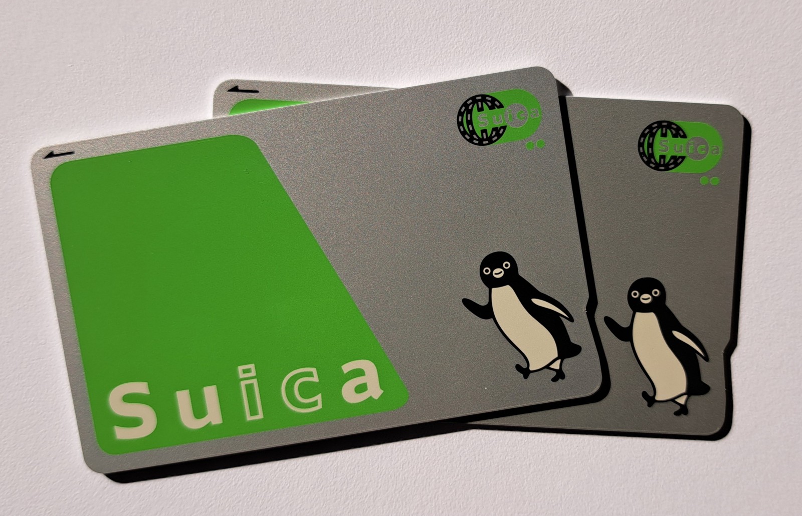 Three Suica transit cards stacked on a white surface, showing penguin mascot designs.
