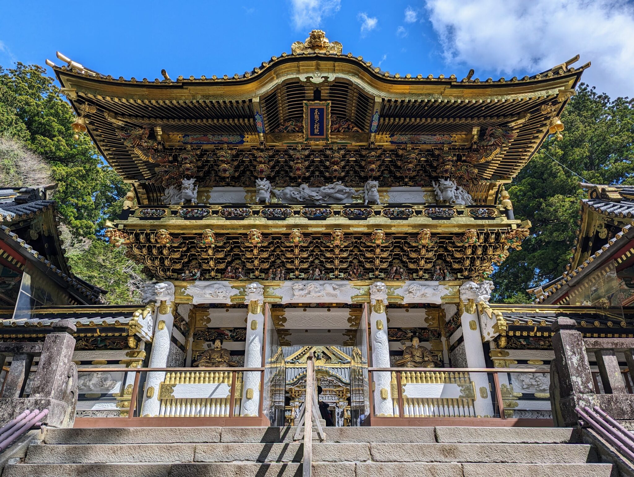 Golden two-story Yomeimon gate of Toshogu Shrine with stone steps and blue sky