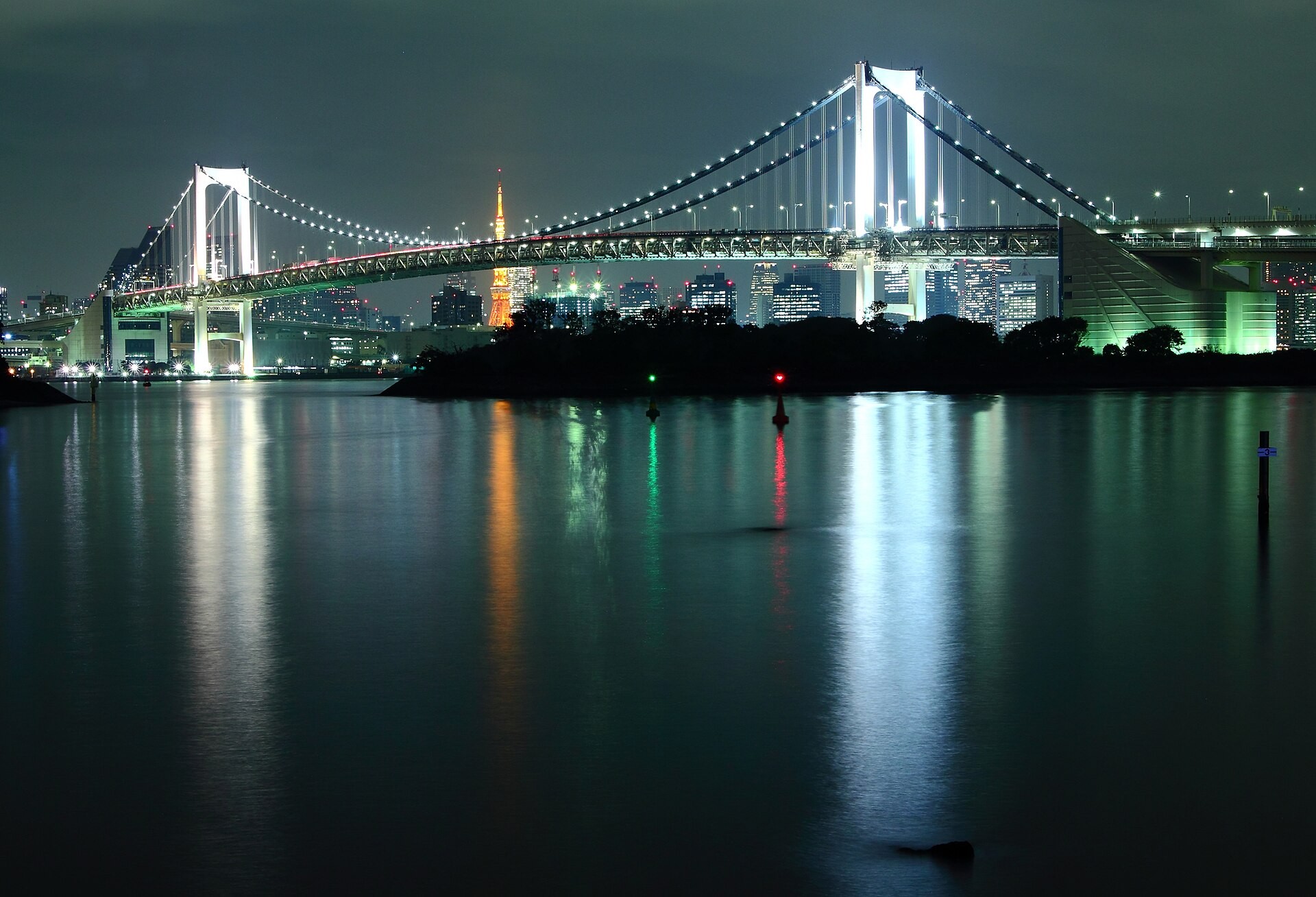 夜の水面に映る白くライトアップされた レインボーブリッジと、遠くに見える東京タワー