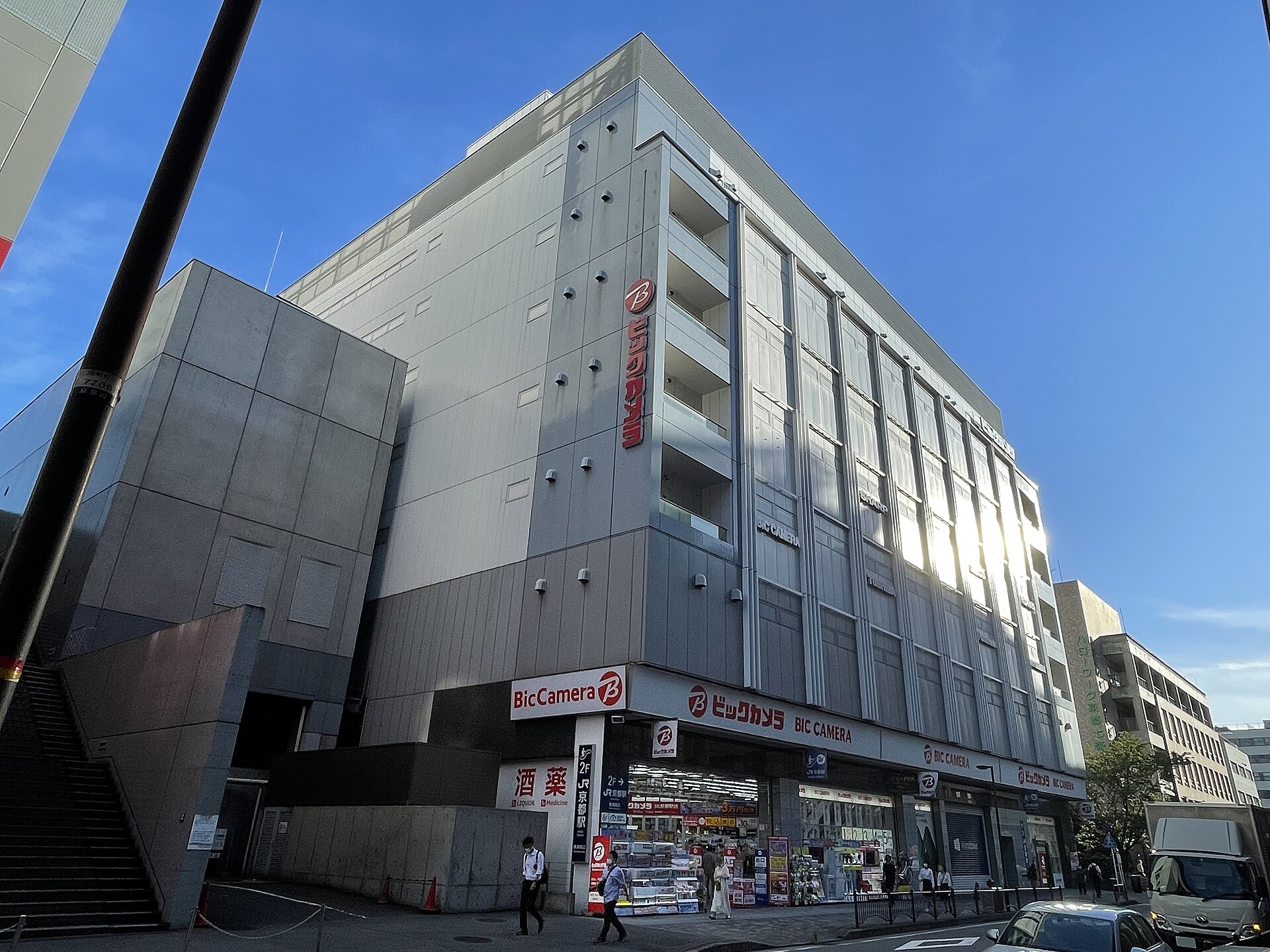 Exterior of the Bic Camera store building in Kyoto, a multi-story gray building under blue sky