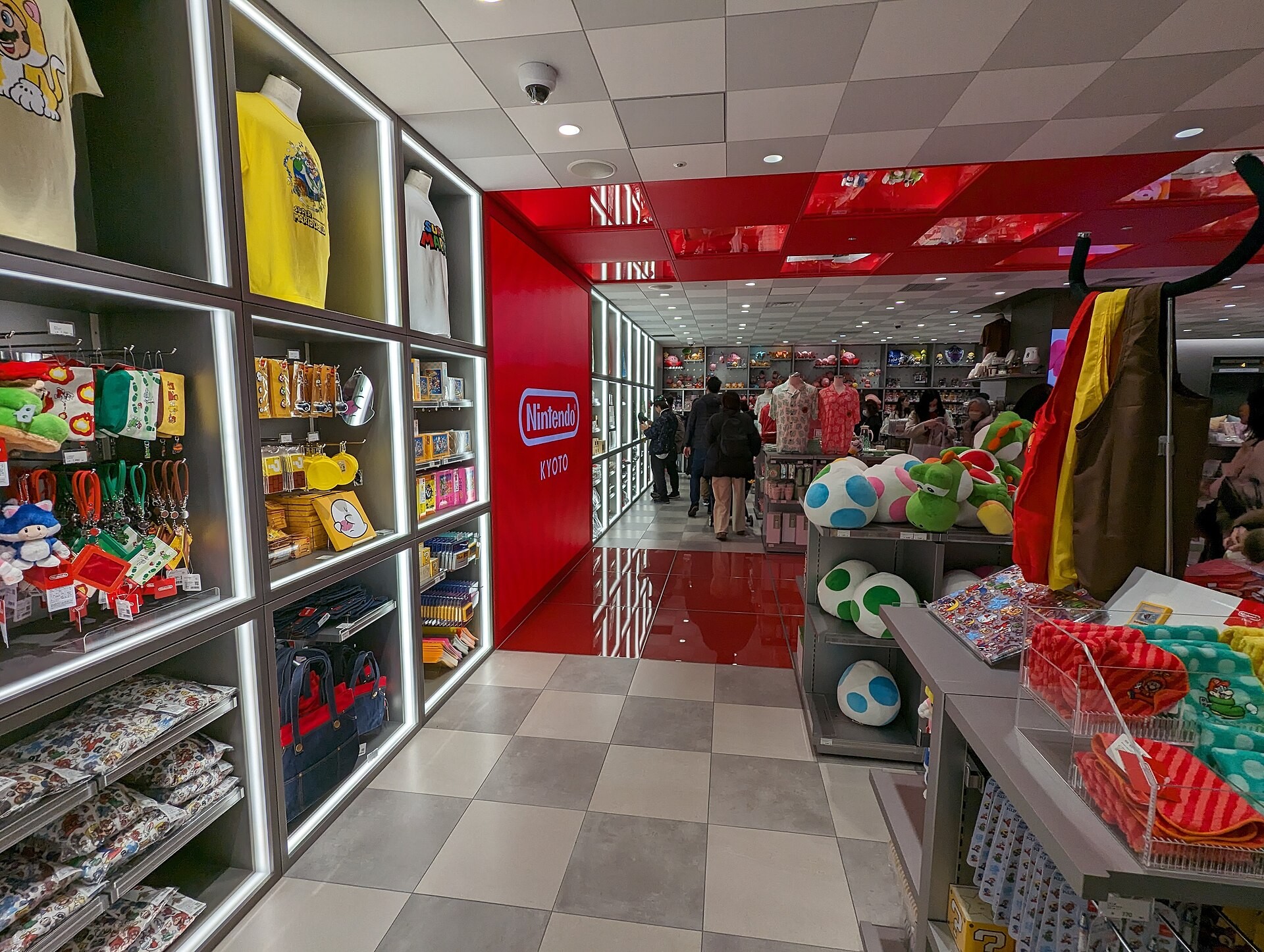 Interior of a Nintendo store with plush toys, merchandise shelves, and a red entrance corridor